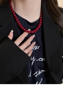 Close-up of elegant red beaded necklace worn with a black blazer for a vintage look.