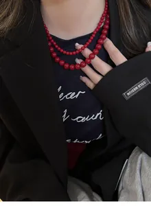 Detailed close-up of a double-layered red bead necklace paired with a black blazer.