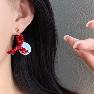 Close-up detail of vintage red acrylic beaded geometric earrings with white disc shell