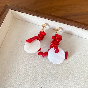 Close-up of elegant red acrylic beaded earrings with white shell-like discs