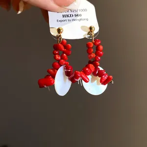 Close-up of elegant red and white beaded earrings with 925 silver needle on a display tag