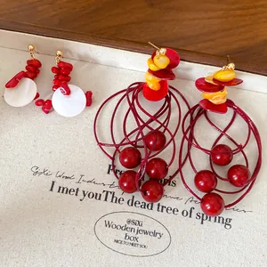 Close-up of elegant red and yellow geometric beaded tassel earrings displayed in a wooden box