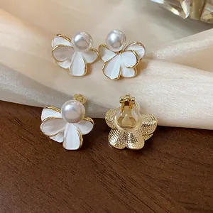 Dettaglio di orecchini a fiore con perle placcati oro 18k con meccanismo a clip posteriore