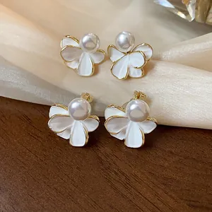 Dettaglio ravvicinato di orecchini a fiore con perle placcati oro 18k su legno e seta