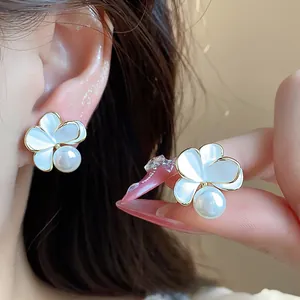 Primo piano di un elegante orecchino a fiore placcato oro 18k con una perla bianca