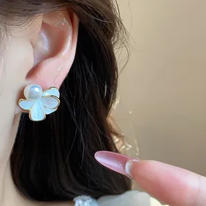 Primo piano di un orecchino a fiore placcato in oro 18k con una perla bianca centrale