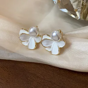Dettaglio ravvicinato di eleganti orecchini a fiore con perle e bordi dorati su seta