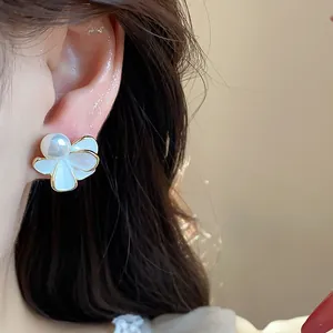Dettaglio ravvicinato di un elegante orecchino a lobo fiore bianco con perla 18k