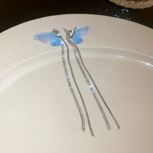 Detailed macro view of blue mesh butterfly wing earrings with long sparkling tassels