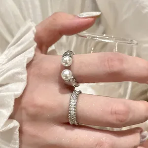 Detail shot of a textured open ring with pearls and a sparkling zircon eternity band