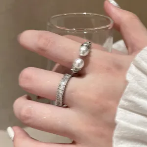 Detailed close-up showing stylish textured silver rings with zircon and pearls on finger