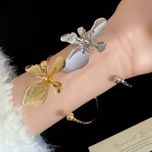 Macro detail view of vintage gold and silver metal flower bangles on a model wrist