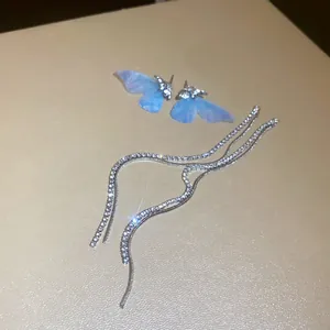 Macro detail of light blue mesh butterfly wing earrings with long sparkling rhinestone tassel chains