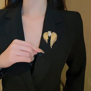Élégante broche en forme d'ailes dorées avec cristaux brillants sur un blazer noir