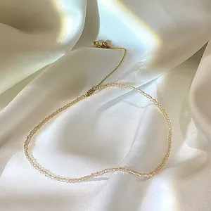 Nahaufnahme einer eleganten champagnerfarbenen Kristallperlenkette auf weißem Satin