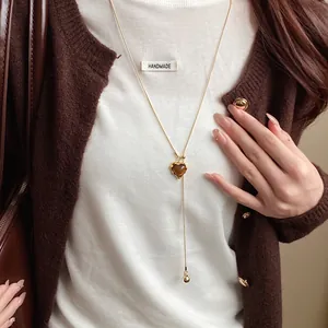 Close-up of a retro Maillard style heart resin pendant necklace worn with a white knit top