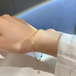 Detailansicht eines zarten Kristallarmbands mit goldener Verlängerung am Handgelenk.