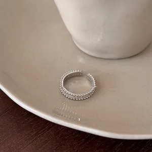 Close-up detail of a silver-toned open ring featuring zircon stones and a beaded texture