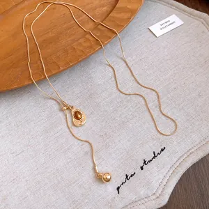 Vintage gold necklace with an elegant oval amber resin pendant and small metal ball