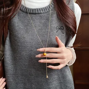 Elegant Maillard style resin bead necklace detail on model wearing a grey knit vest
