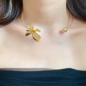 Close-up detail of an elegant gold metal flower choker necklace worn by a model