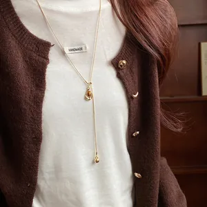Close-up of vintage gold Y-necklace with oval resin pendant on model