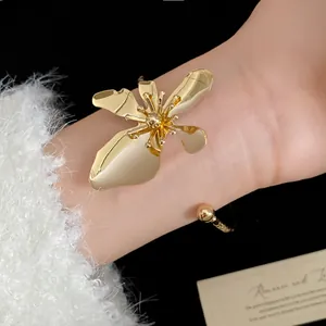 Detailed close-up view of a vintage gold metal flower bracelet worn on a female wrist