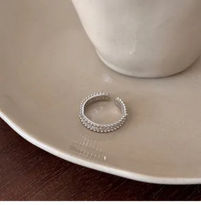 Close-up of a silver open ring featuring zircon inlay and beaded pearl texture.