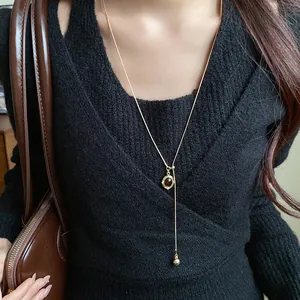 Close-up of vintage oval resin pendant necklace paired with a black knit sweater and bag