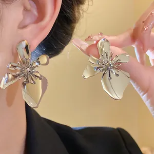 Detailed view of oversized vintage silver metallic flower earrings worn and held