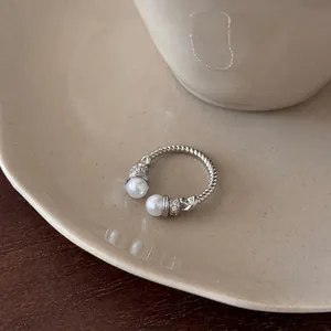 Detailed close-up of an elegant silver textured open ring with twin pearls and zircon accents