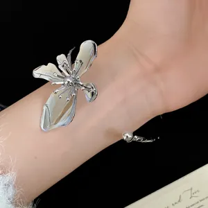 Close-up detail of an elegant vintage silver metal flower cuff bracelet on a model's wrist.