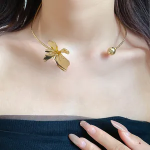 Close-up of a vintage golden metal flower choker necklace worn by a female model.