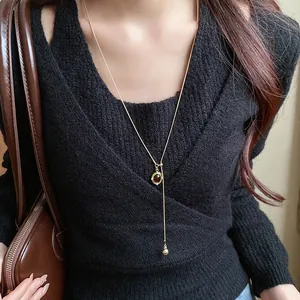 Detail of a vintage oval resin pendant Y-necklace worn on a black knit sweater