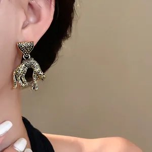 Vintage gold leopard earrings with triangle studs, worn by model for high-end look.