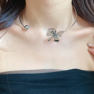 Detail shot of a minimalist silver metal flower choker necklace on a female model.