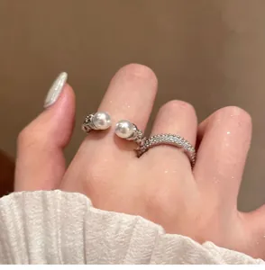 Detailed view of elegant pearl and zircon open ring on finger in soft lighting