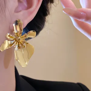 Detail view of large gold metallic flower earring worn on ear for a vintage look