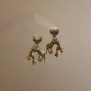 Close-up detail of vintage-style leopard drop earrings with engraved gold texture