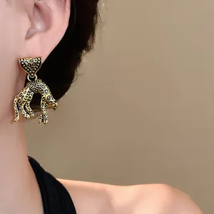 Close-up view of vintage style gold panther drop earrings with black leopard spots.