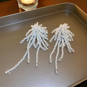Macro view showing the intricate details of white pearl and crystal beaded tassel earrings.