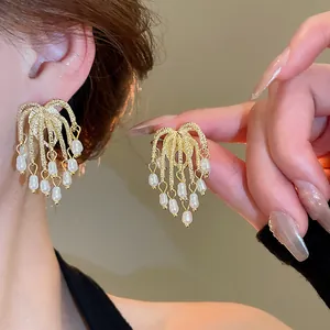 Detail of gold tassel stud earrings featuring elegant white pearls and silver needles