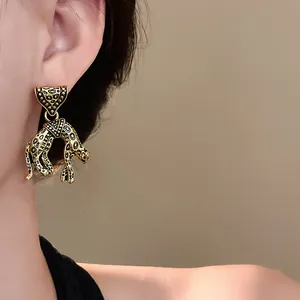 Close-up of vintage leopard dangle earrings with a gold-tone antique finish