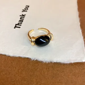 Primer plano de un anillo dorado vintage con una piedra negra óvalo sobre tarjeta Thank You.