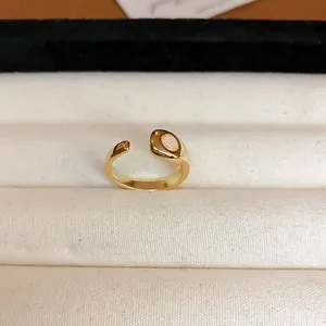 Primer plano de un anillo geométrico dorado vintage con elegante incrustación de esmalte blanco