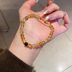 Detailed view of yellow crystal and agate beaded bracelet with a gold flower charm