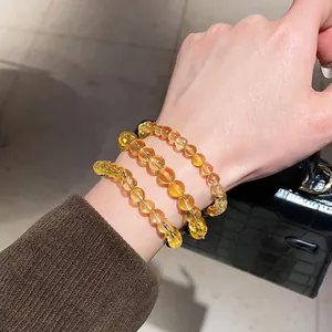 Detailed view of yellow crystal beaded bracelets on a wrist in elegant Maillard style