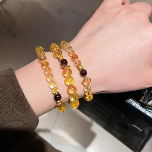 Detailed view of yellow citrine and red agate beaded bracelets with gold flower charms