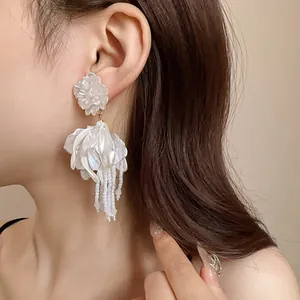 Detailed shot of elegant white petal earrings with cascading crystal tassels on model