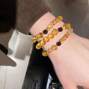 Close-up view of elegant citrine and agate bead bracelets with golden flower spacers on wrist